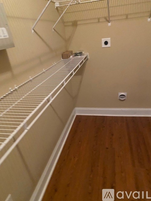 A walk-in closet with a metal shelf and wooden floors.