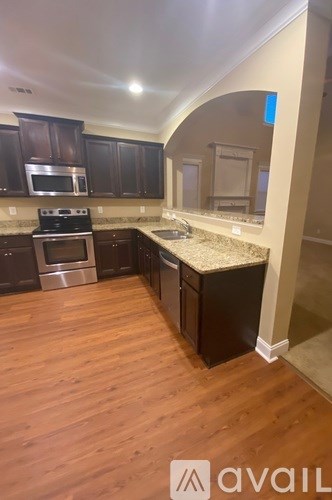 A kitchen with wooden floors and dark brown cabinets.