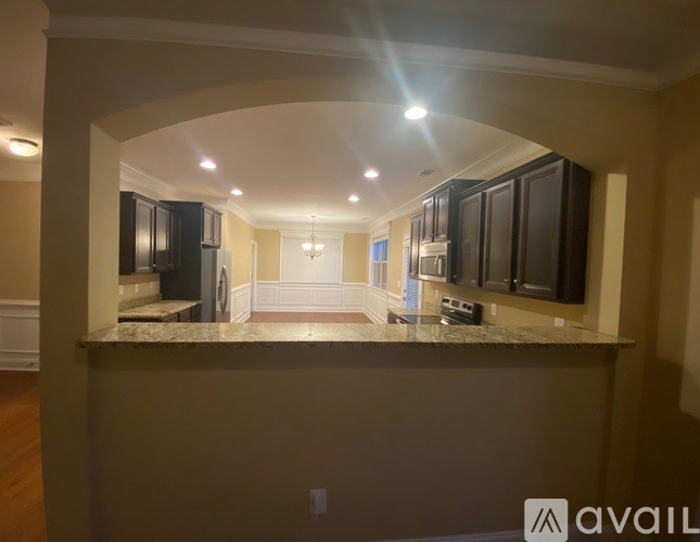 A kitchen with a marble countertop and dark cabinets.