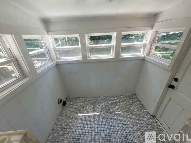A bathroom with a tiled floor and three windows.