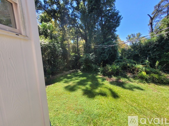 A view from a window looking out to a green lawn and trees.