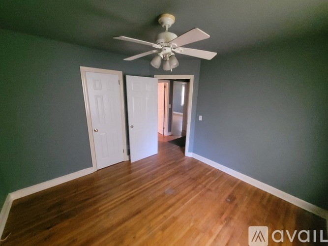 A room with a ceiling fan and wooden flooring.