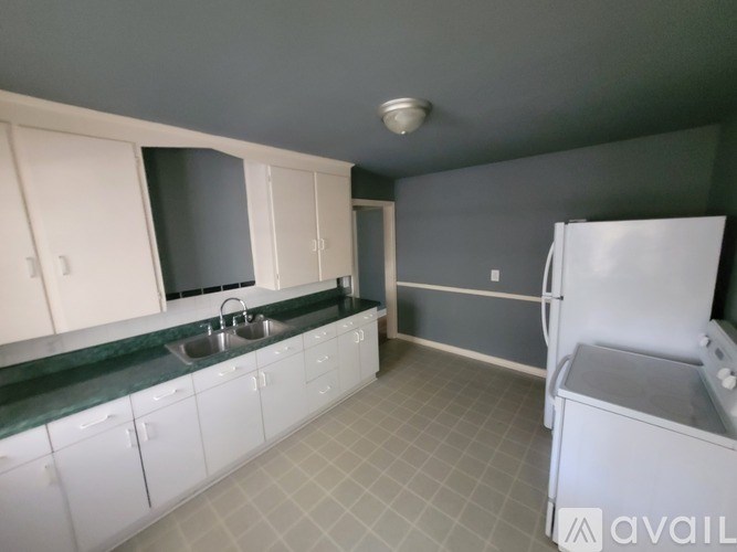 A kitchen with white cabinets and a green countertop.