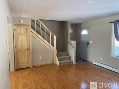 A room with wooden floors and a staircase leading to another room.
