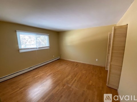 A room with wooden flooring and a window with blinds.