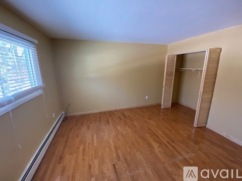 A room with wooden flooring and a window with blinds.
