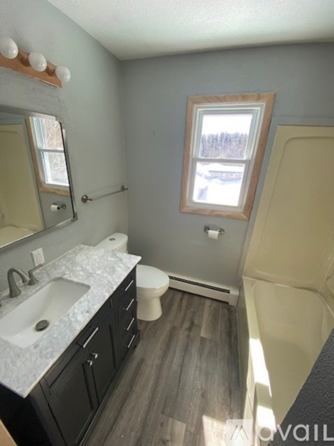 A bathroom with a sink, toilet, and window.