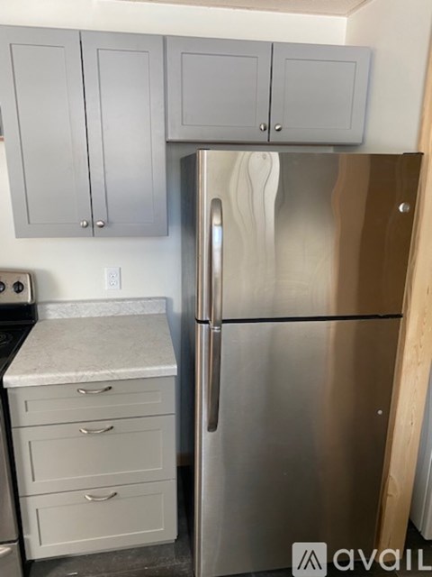 A kitchen with a stainless steel refrigerator and cabinets.