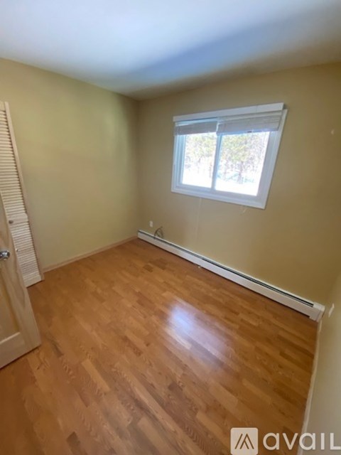 A room with wooden flooring and a window.