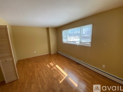 A room with wooden flooring and a window with blinds.