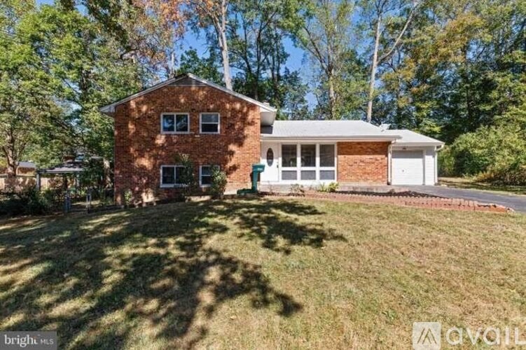 A house with a white garage door is surrounded by trees.