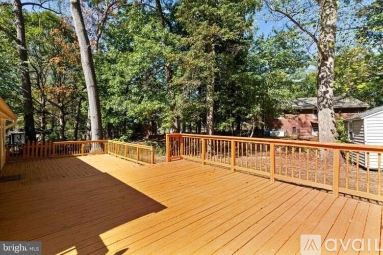 A wooden deck with a railing and trees in the background.