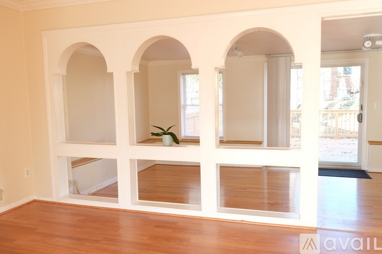 A room with wooden floors and white walls with three arched windows.