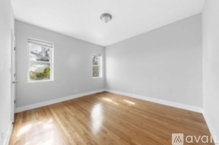 A room with wooden flooring and a window showing a view of a landscape.
