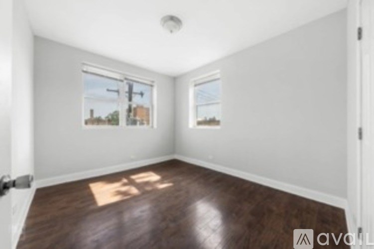 A room with wooden floors and white walls, with a window showing a street view.