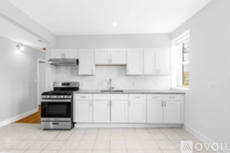 A kitchen with white cabinets and a stove top oven.