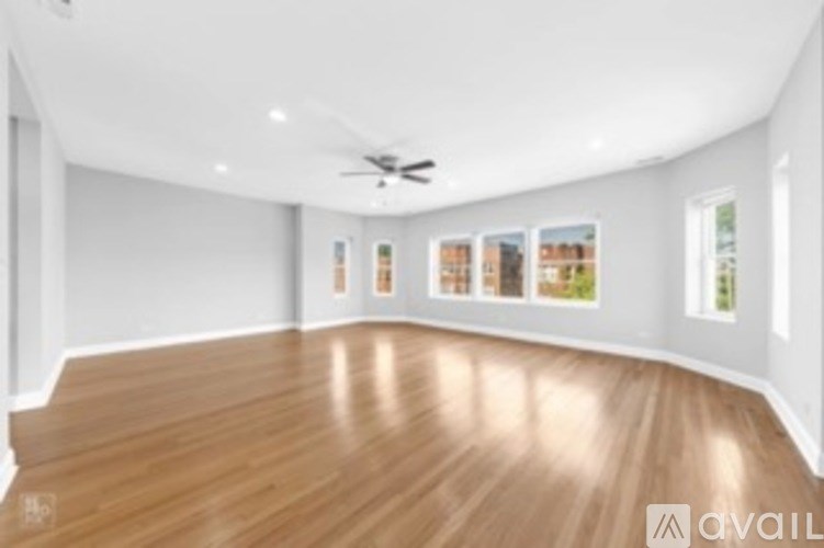 A spacious room with wooden flooring and a ceiling fan.