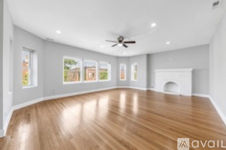 A spacious room with wooden flooring and a ceiling fan.