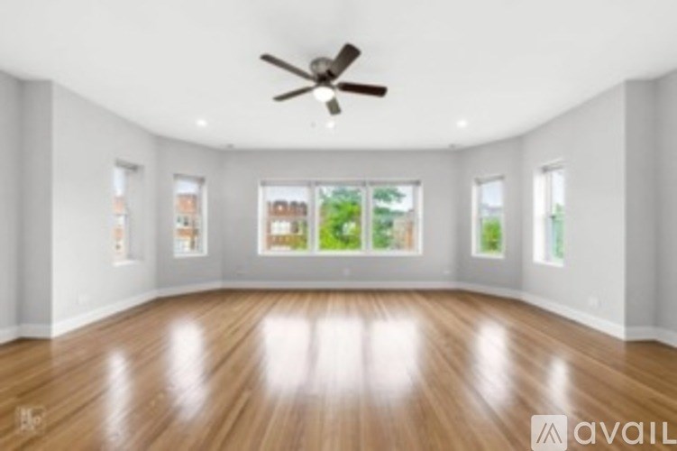 A spacious room with wooden floors and a ceiling fan.