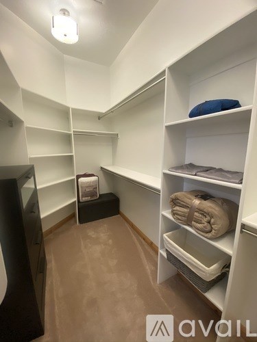 A small, white closet with shelves and a black chair.