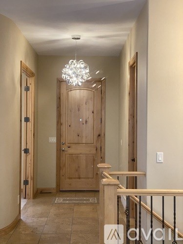 A hallway with a wooden door and a chandelier hanging from the ceiling.