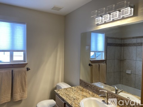 A bathroom with a granite countertop and a large mirror.
