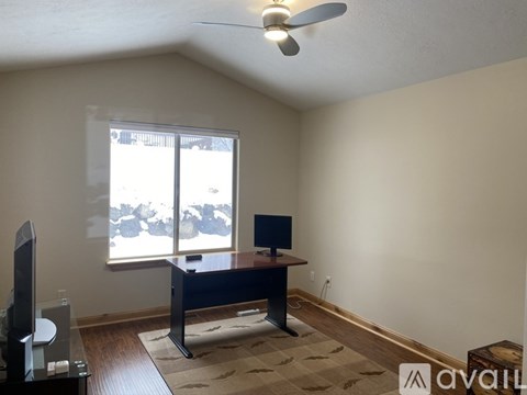 A room with a desk and a fan.