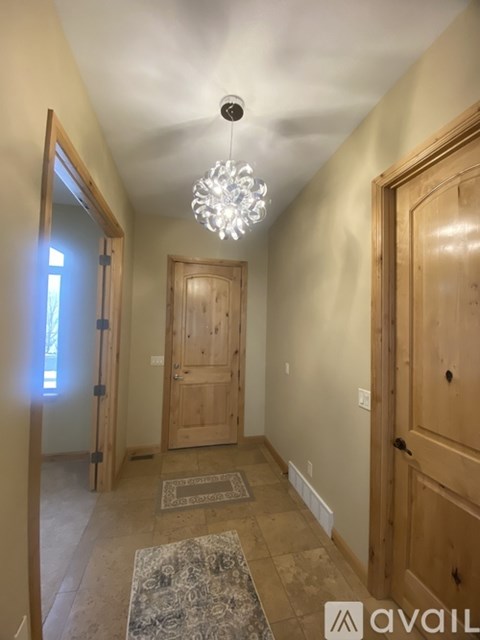 A hallway with a rug and a chandelier.