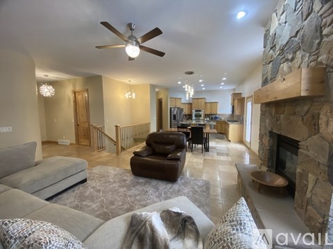 A living room with a stone fireplace and a ceiling fan.