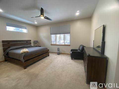 A bedroom with a bed, chair, and television.