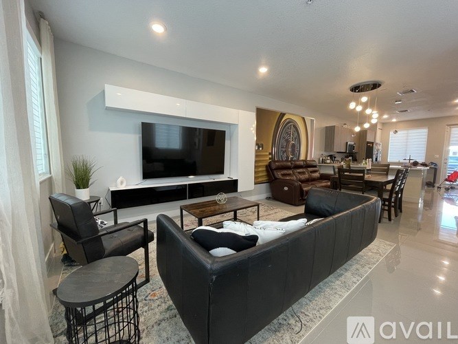A modern living room with a large black sofa and a flat screen TV mounted on the wall.