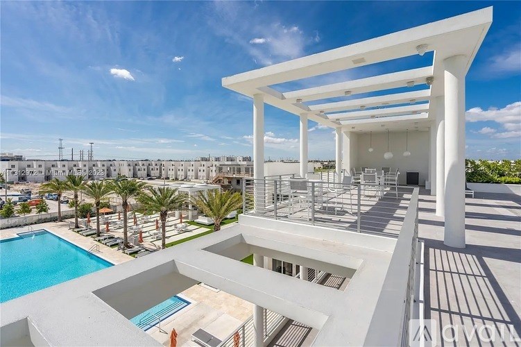 A modern white building with a pool and a sunny sky.