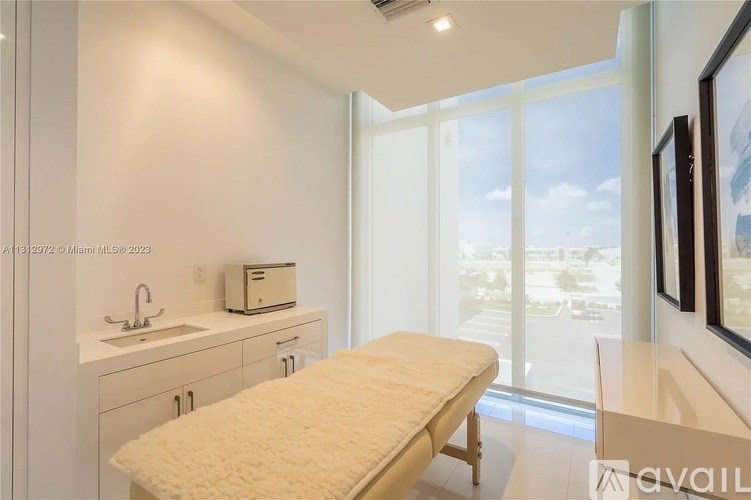 A white room with a bed, sink, and window.