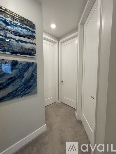 A hallway with a painting on the wall and a door on the right.