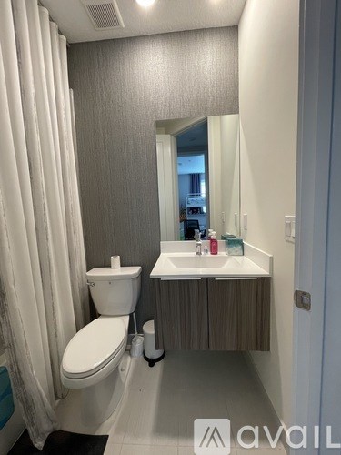 A bathroom with a toilet, sink, and mirror.