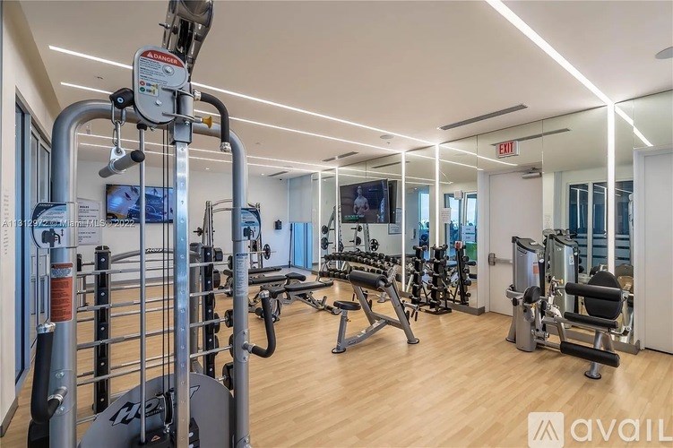 A gym with a variety of equipment including a treadmill, weights, and a television.