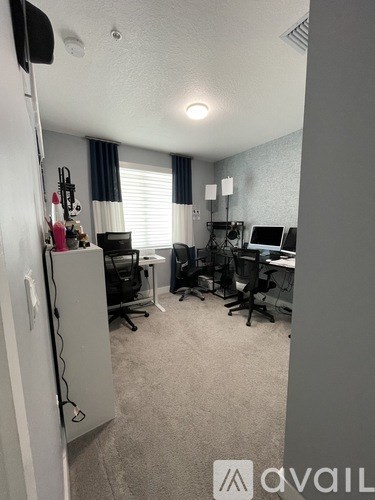 A room with a desk, chairs, and computer equipment.
