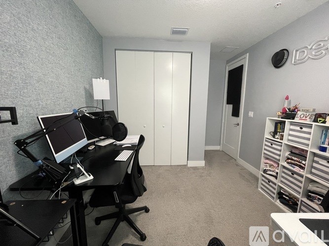 A room with a desk, computer, and chair.