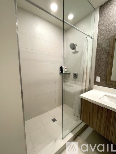 A bathroom with a glass shower stall and a white sink.