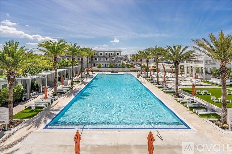 A large outdoor swimming pool surrounded by palm trees and lounge chairs.
