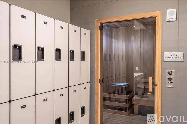 A row of white lockers with a door to a room with a bench and a sign that says "Spauna Maximum?".