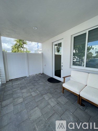 A patio with a white couch and a black mat.