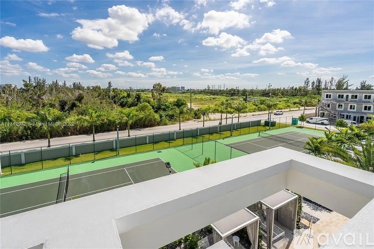Tennis courts on a sunny day with a building in the background.