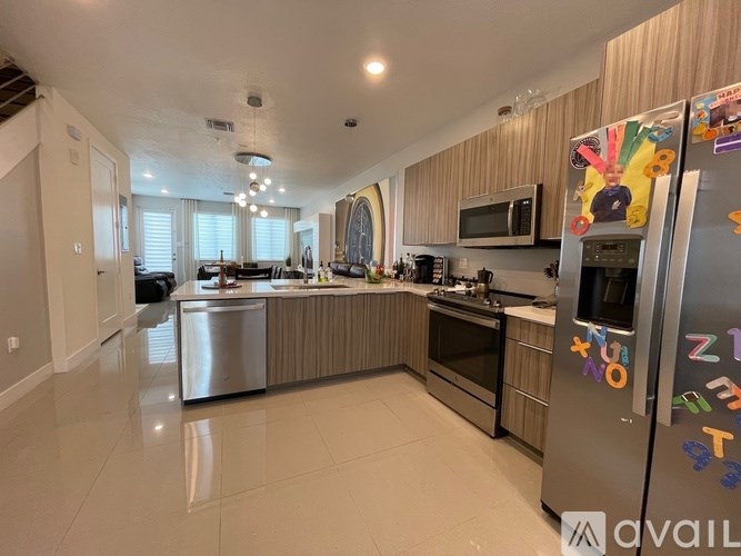 A modern kitchen with a refrigerator covered in colorful magnets.