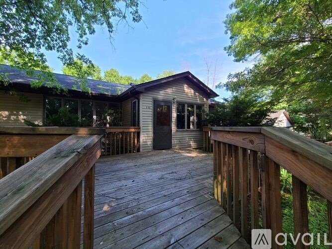 A wooden deck leads to a small cabin in a wooded area.