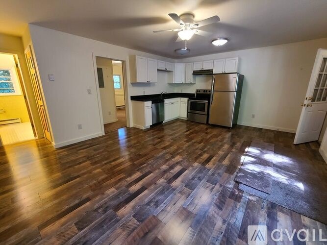 A kitchen with a refrigerator, cabinets, and a ceiling fan.