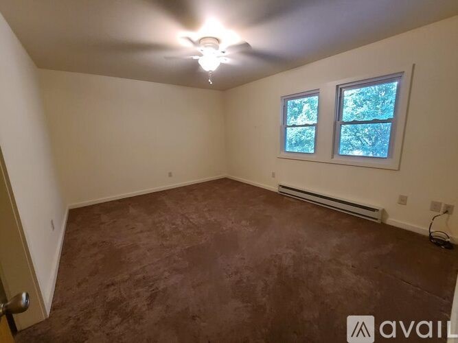 A room with brown carpet and a ceiling fan.