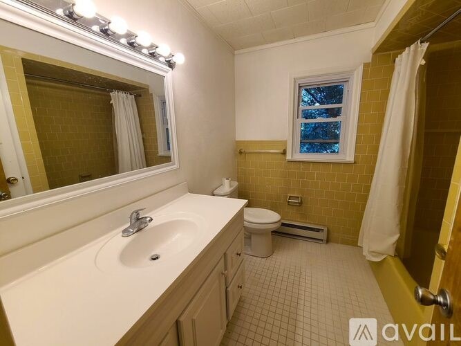 A bathroom with a sink, toilet, and mirror.