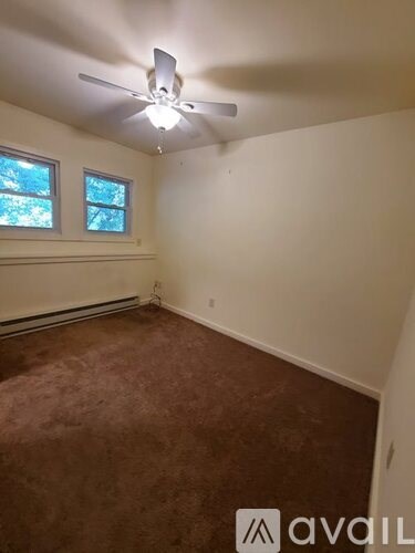 A room with a ceiling fan and two windows.