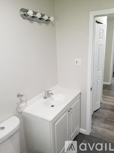 A white bathroom with a toilet, sink and a light switch.